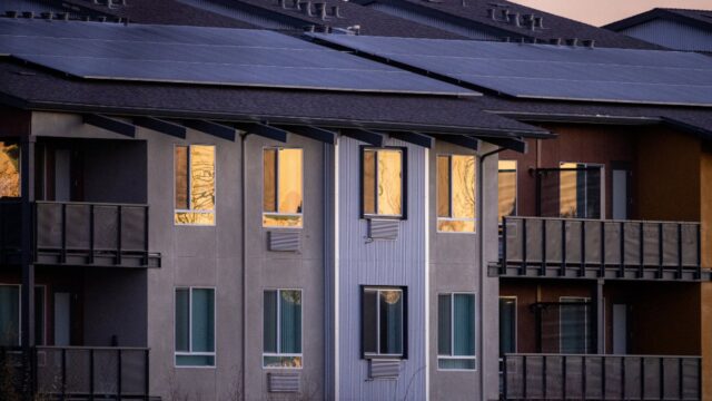 Mehrfamilienhaus mit Balkonen und Solarmodulen auf dem Dach
